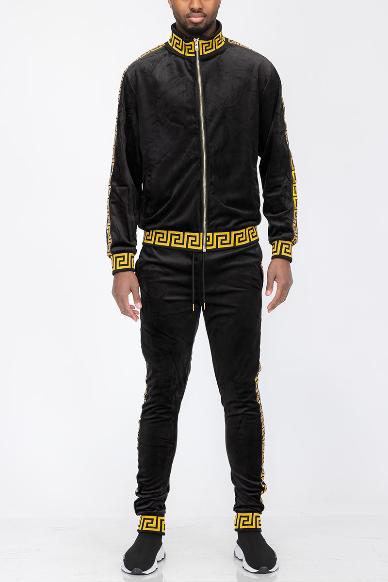Black tracksuit with gold detailing worn by a person on a white background