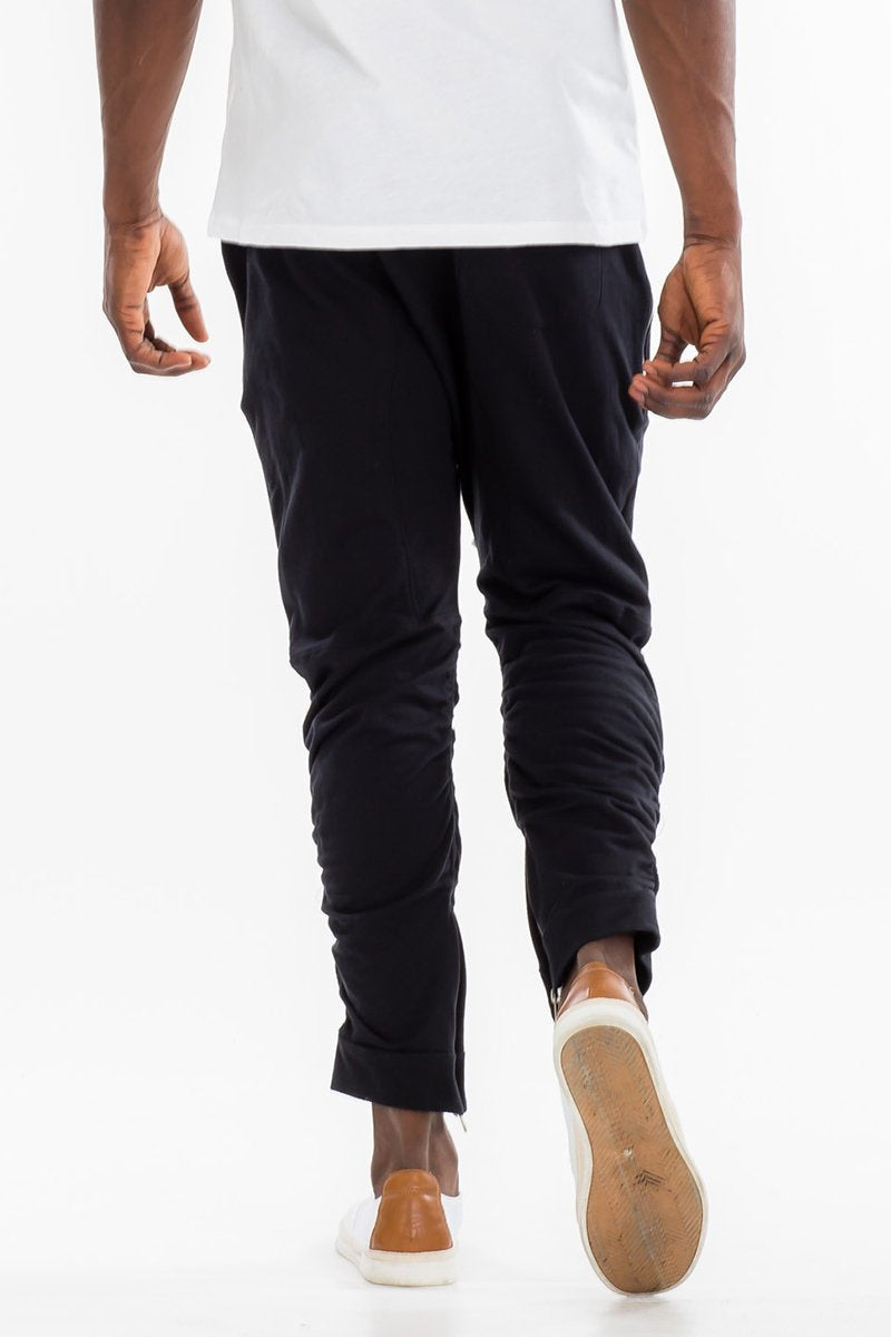 Person wearing black pants and white shoes on a white background