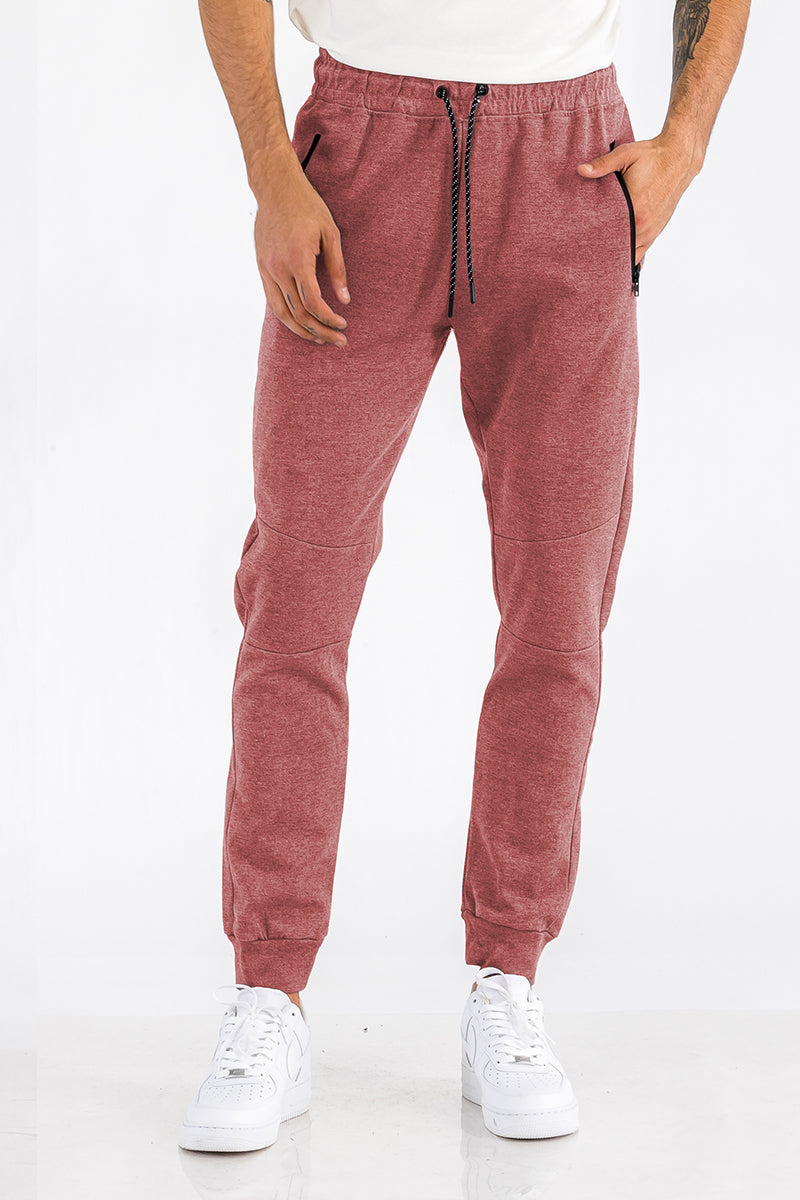 Person wearing maroon jogger pants and white sneakers on a white background