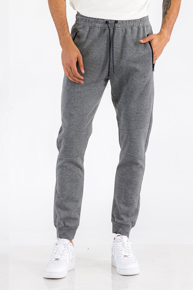 Person wearing gray sweatpants and white sneakers on a white background