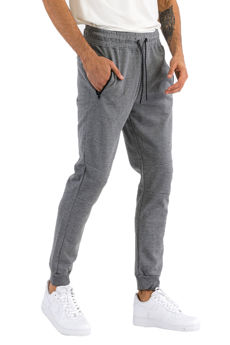 Person wearing gray jogger pants with a white background