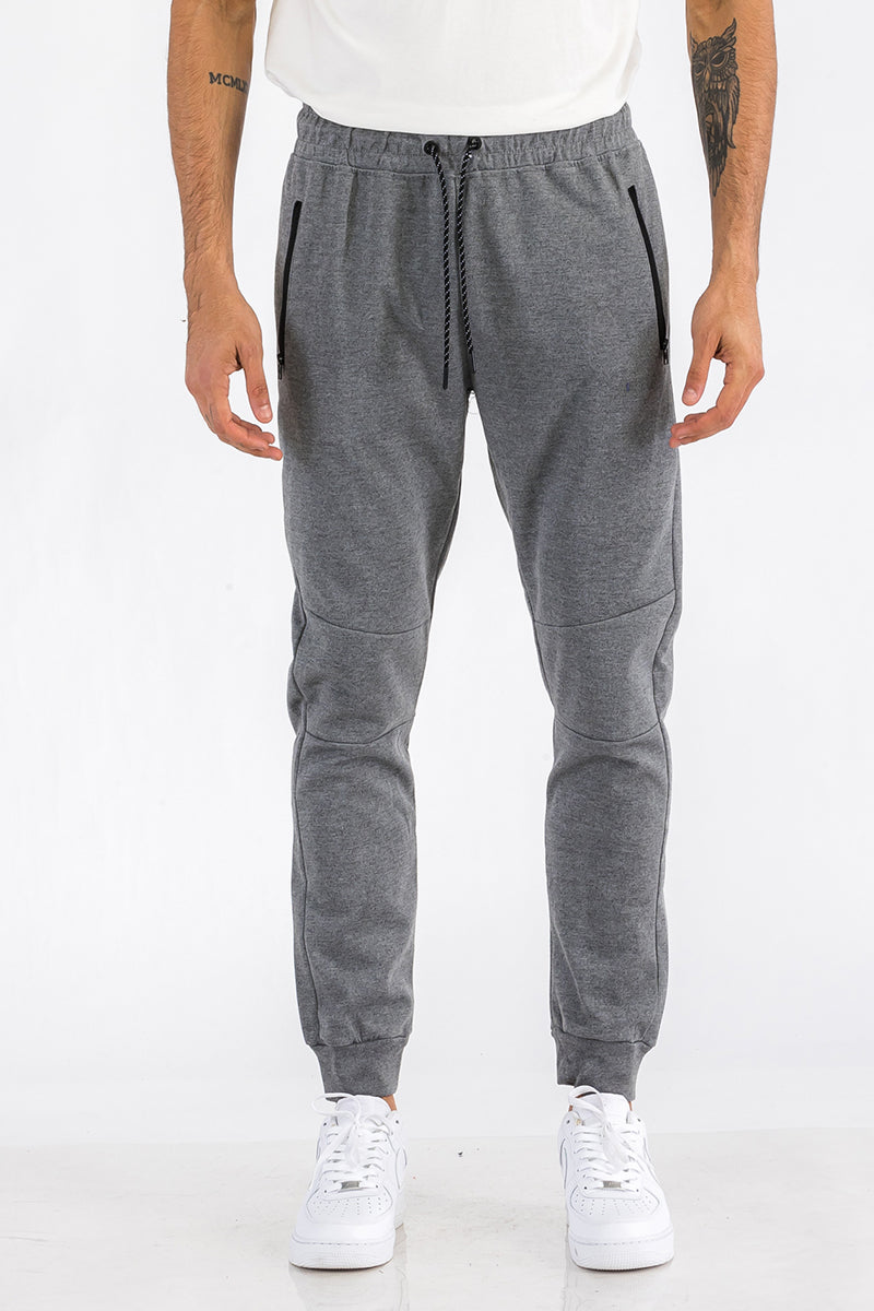 Person wearing gray jogger pants on a white background
